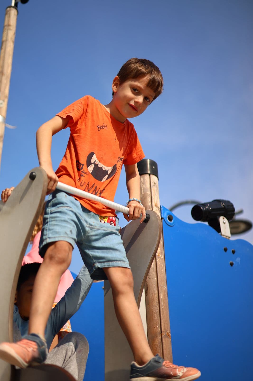 Un enfant grimpe en toute autonomie sur une structure de jeu extérieure