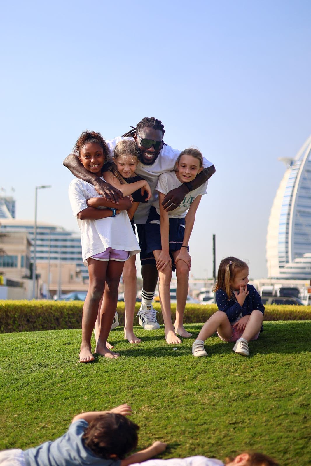 Ronald, fondateur des Aventuriers DXB, entouré d'un groupe d'enfants devant le Burj Al Arab à Dubaï